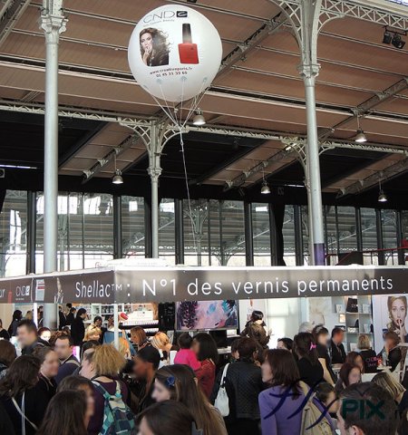 Ballon hélium publicitaire sphérique avec marquage personnalisé en impression numérique sur fond blanc, survol d'un stand.