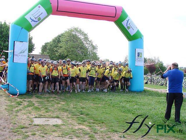 Arche publicitaire personnalisée déployée pendant une compétition sportive, ici une course à pied. Ici, la ligne de départ avec les coureurs.