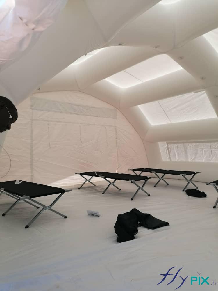Des lits picots pliables pour adultes, à l'intérieur d'une tente PMA gonflable air captif de dimensions 10x6 m.