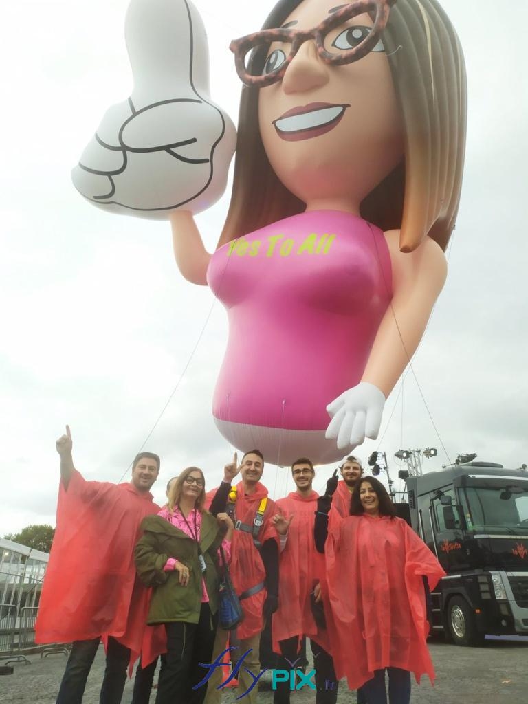 Ballon mascotte Eva Albarran, une mascotte personnalisée représentant un personnage, fabriqué sur mesure par nos soins, avec l'équipe qui a eu la charge de s'occuper de la gestion et du déploiement de la structure gonflable, pendant l'événement en environnement extérieur.