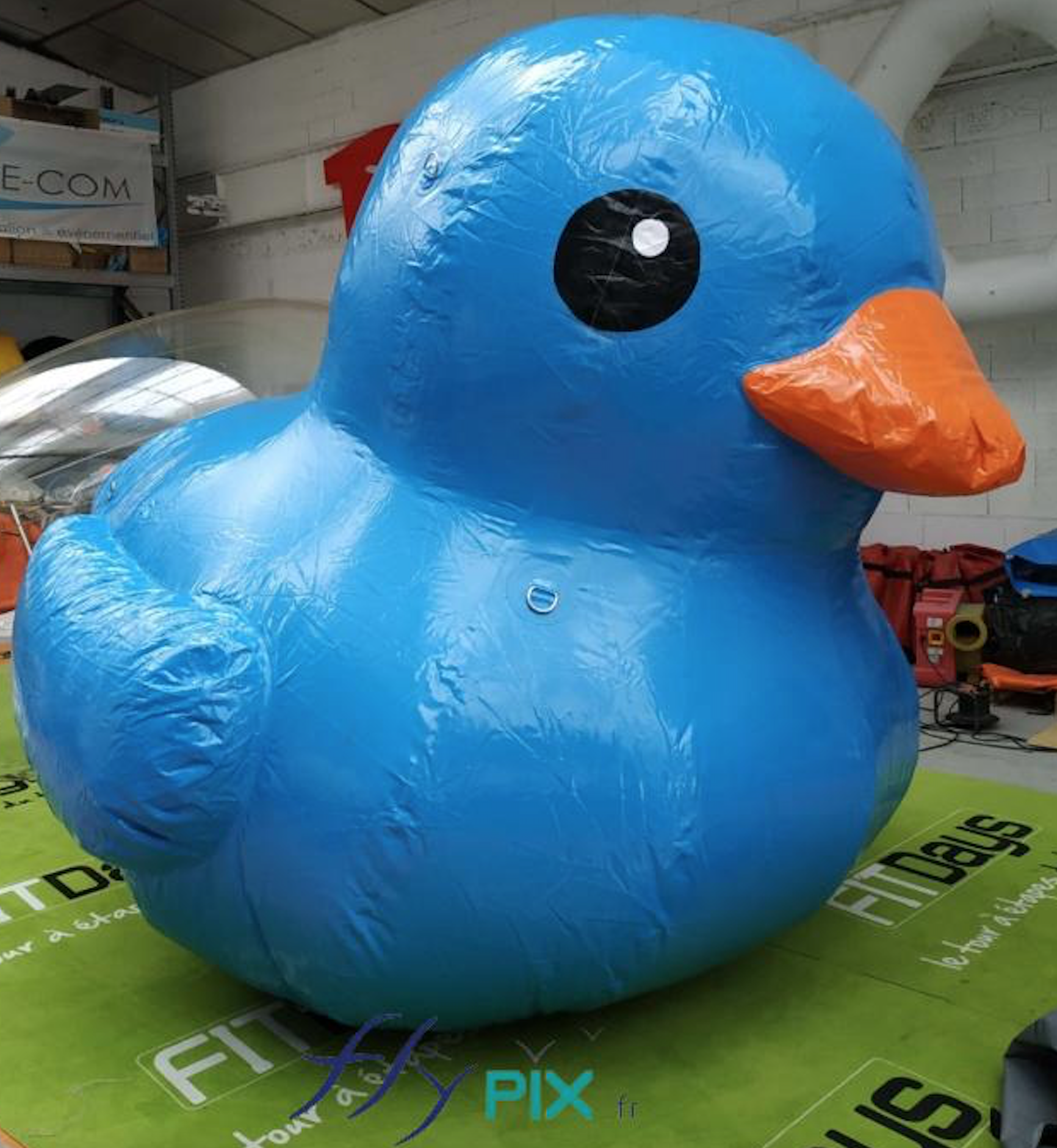 Ballon gonflable mascotte canard géant, de couleur bleu, air captif, en enveloppe PVC, avec un bec jaune.