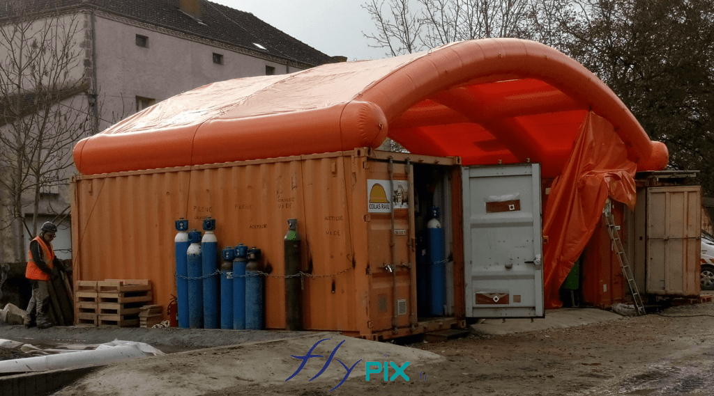 Préau abri gonflable fabriqué en France par nos soins, air captif, PVC 0.6 mm, positionné entre 2 containers maritimes, pour se protéger des intempéries et de la pluie..