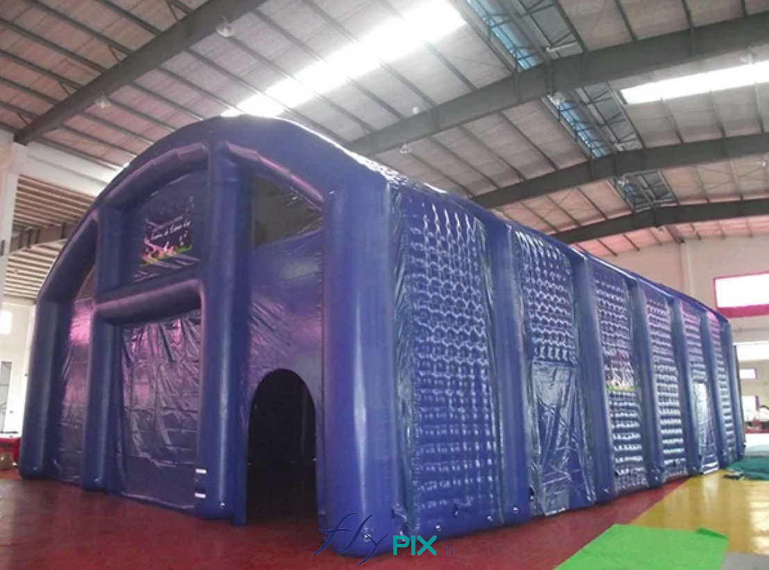 IUT de NANTES : une photo du grand hangar gonflable, en forme de U-inversé, en enveloppe PVC double peau capitonnée, ici déployé dans une salle polyvalente durant une phase de test de déploiement et de gonflage, avant livraison au commanditaire. Nous observons plusieurs accès et portes sur le pignon de la façade avant, et 2 portes d'accès latérales.