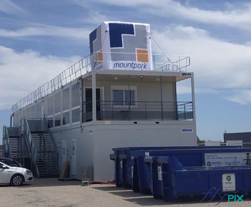 Ballon en forme de cube posé sur le toit d'un algeco, dans un chantier