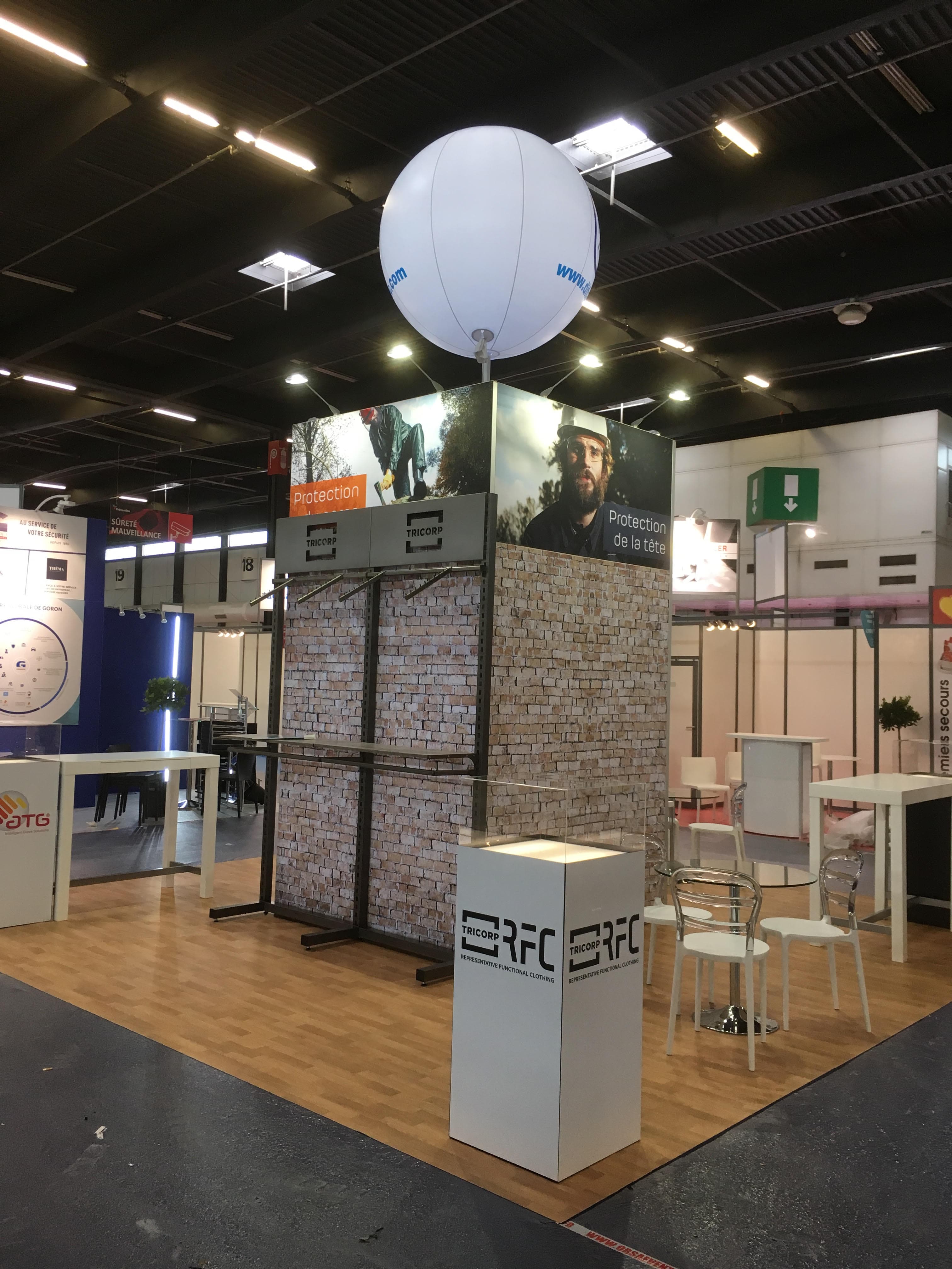 Un ballon sur mat imprimé, de forme sphérique, installé et déployé pour un stand dans un salon professionnel en environnement intérieur.