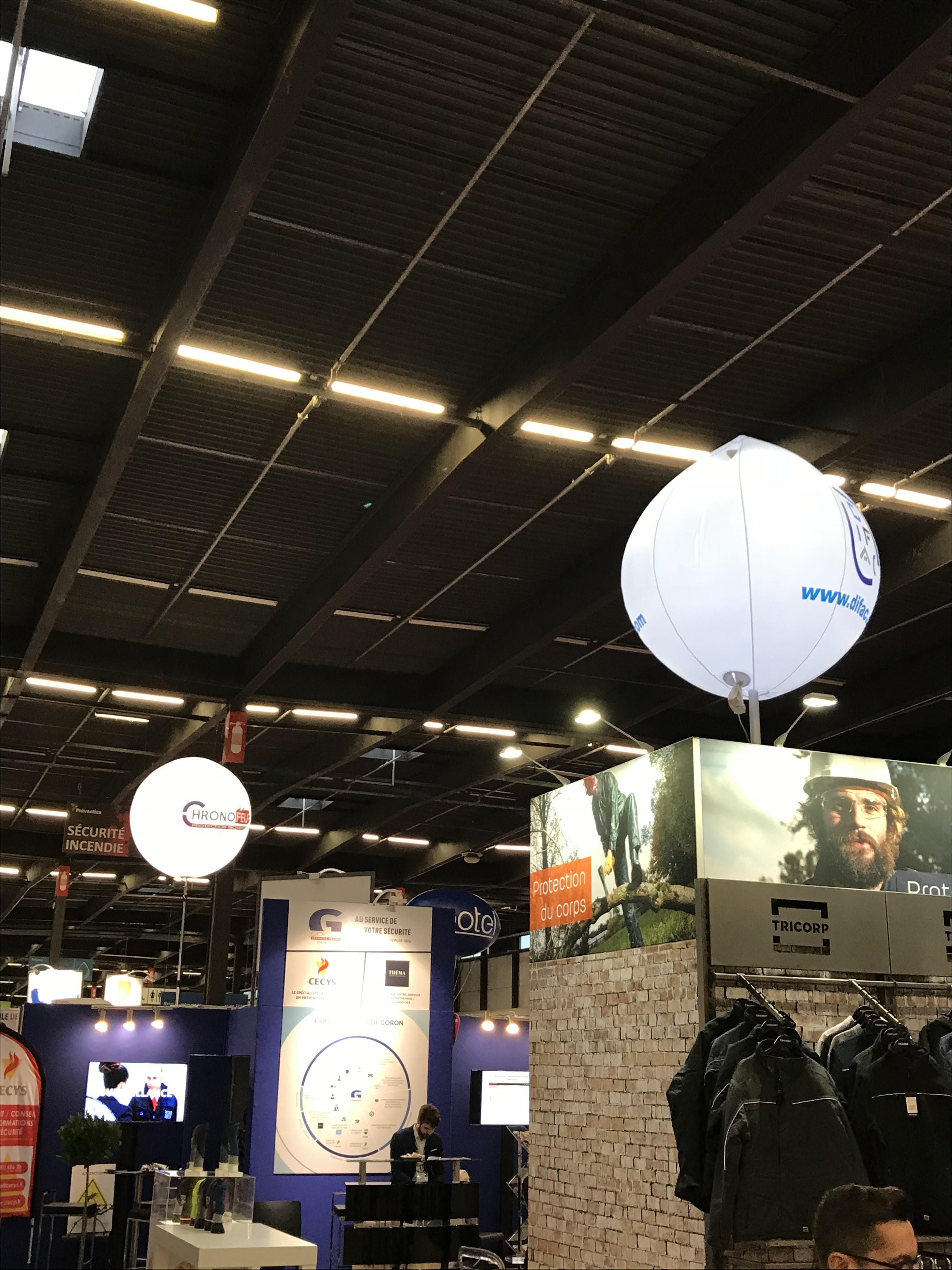 Un ballon sur mat imprimé et éclairant anime le stand dans un salon professionnel, en environnement intérieur.